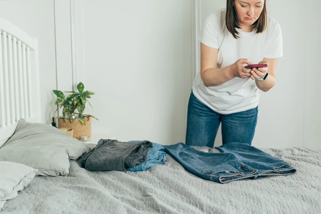 Woman takes pictures of jeans on her bed to sell for emergency funds