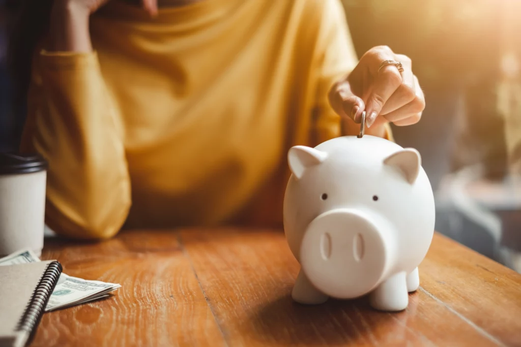 A woman drops a coin into a white piggy bank