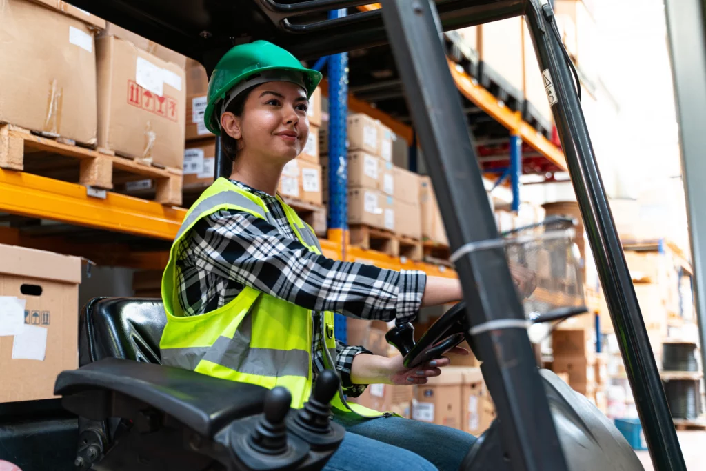 A young person driving a forklift in a warehouse