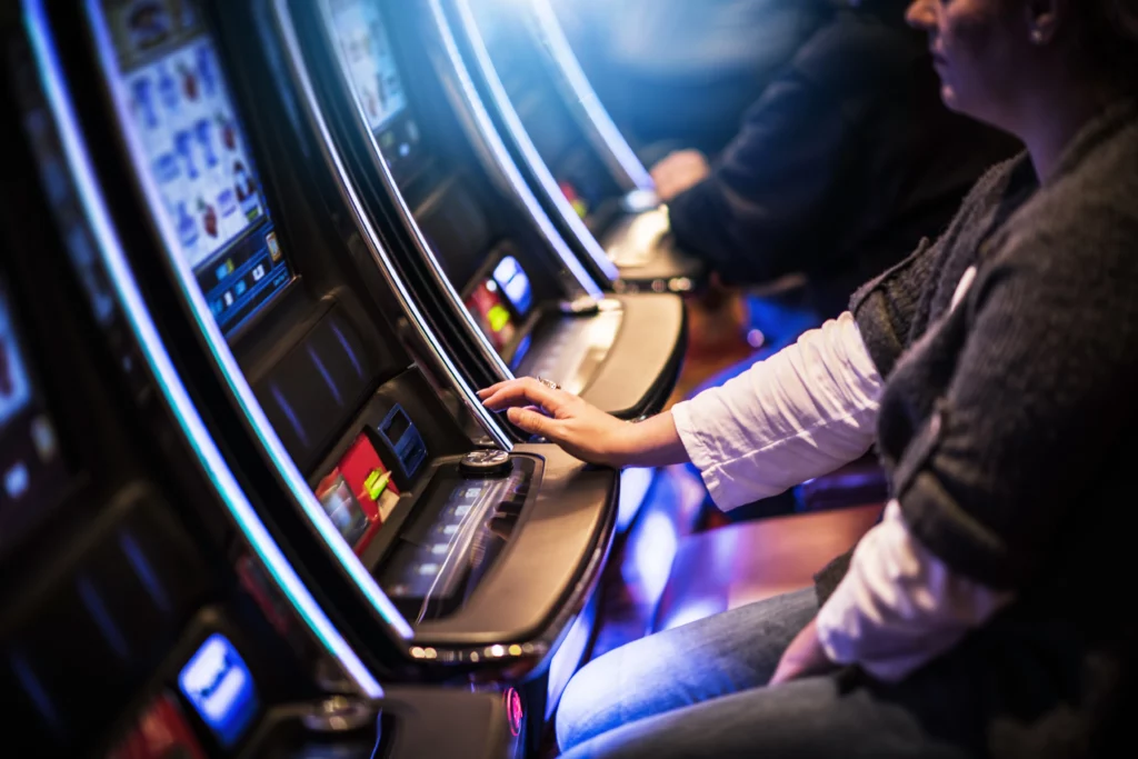 Close up on someone's hands using a pokies machine to gamble