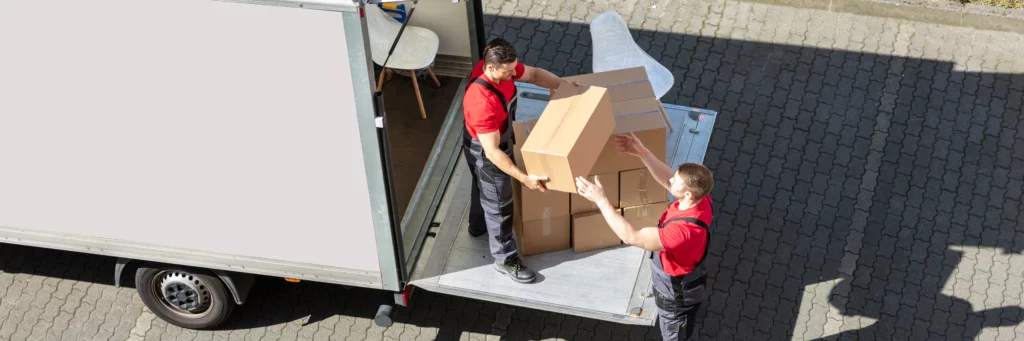 Two removalists stack boxes into a moving truck