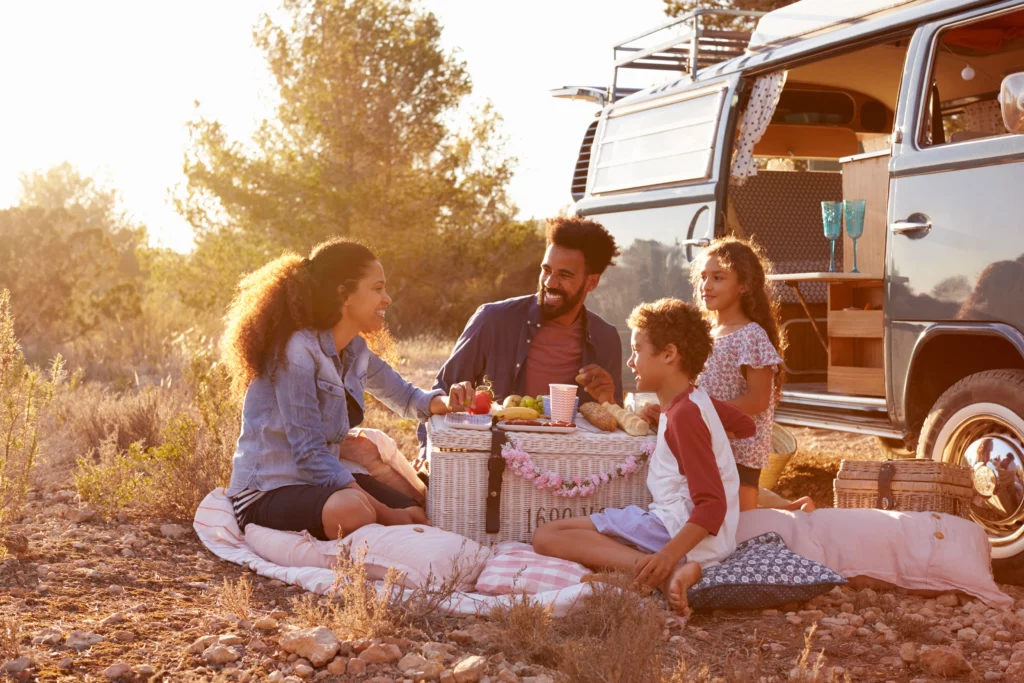 Two parents and two young kids set up a picnic in the bush for camping